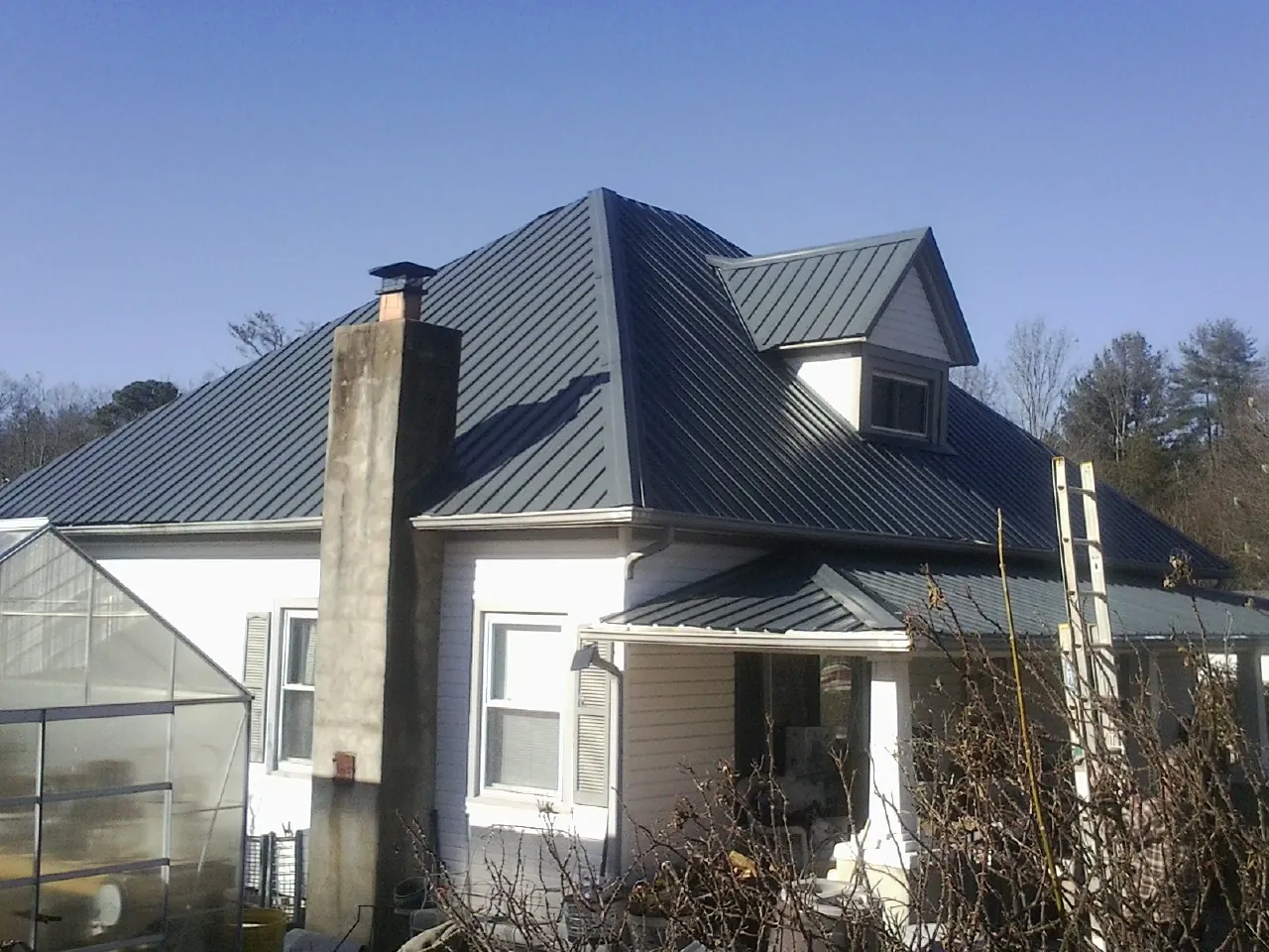 Dark blue standing seam metal roof on a white farmhouse with dormer — Slate & Tile Roof Repair by Roofing Brothers in Boiling Springs