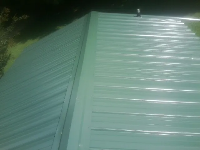 New green metal panels meeting at the ridge of a roof — Flat Roof Repair work by our crew in Boiling Springs