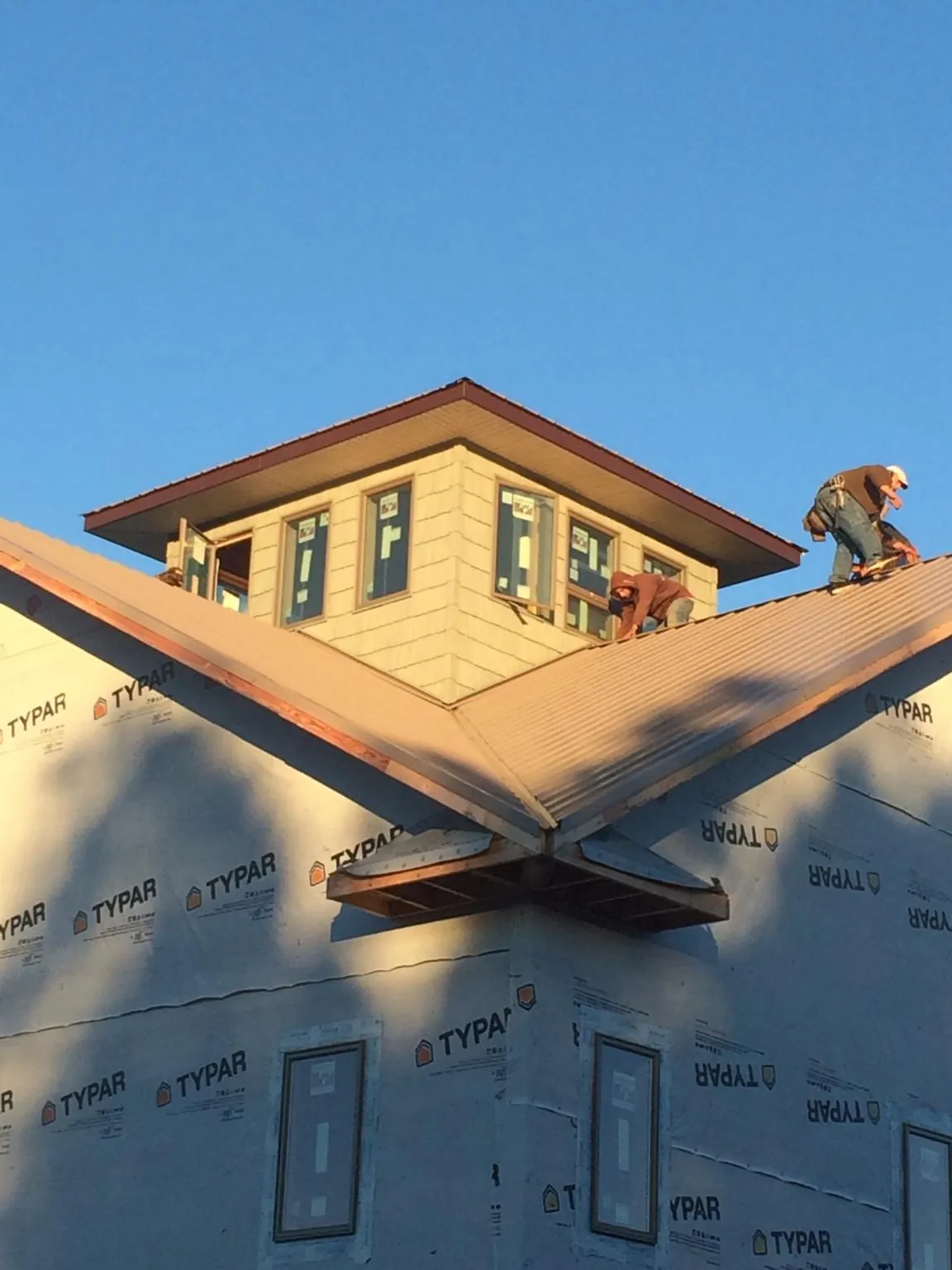 Roofers working around a rooftop cupola on a new metal roof at sunset — Roof Waterproofing in Boiling Springs by Roofing Brothers